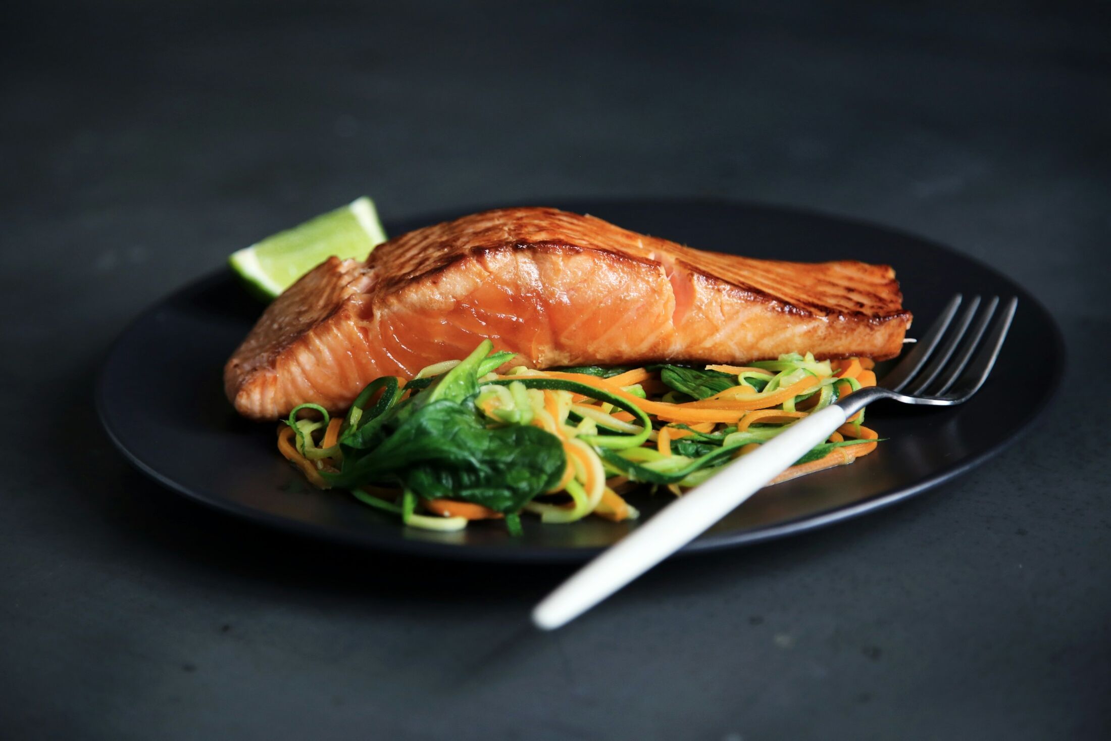 Salmon fillet with vegetables on a dark plate